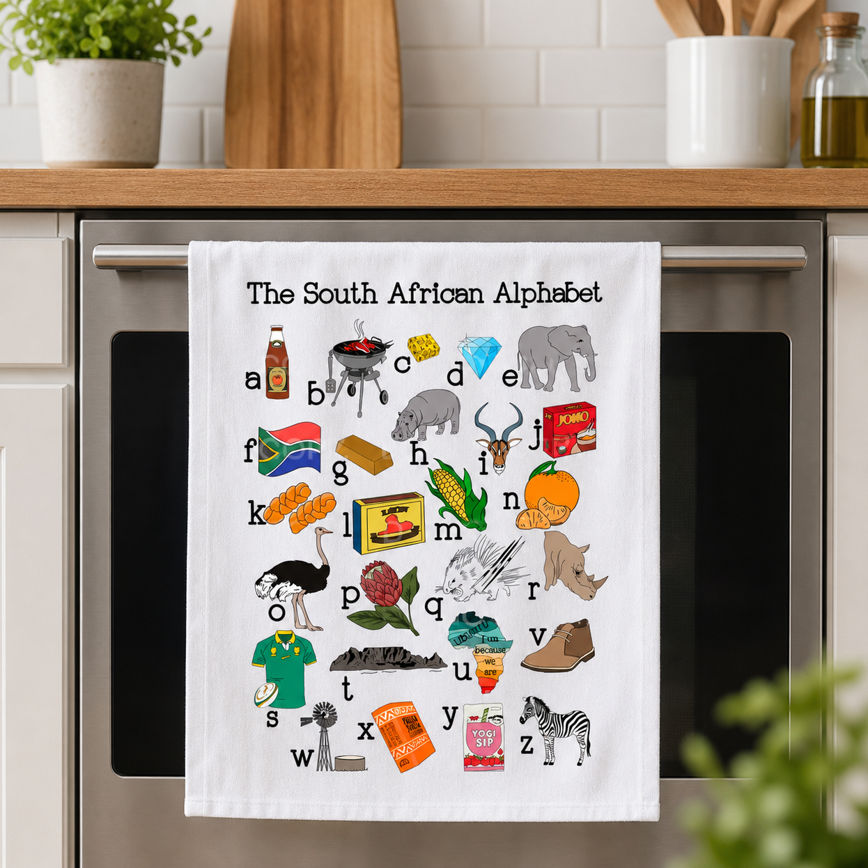 Kitchen towel with South African alphabet design hanging on a kitchen appliance.